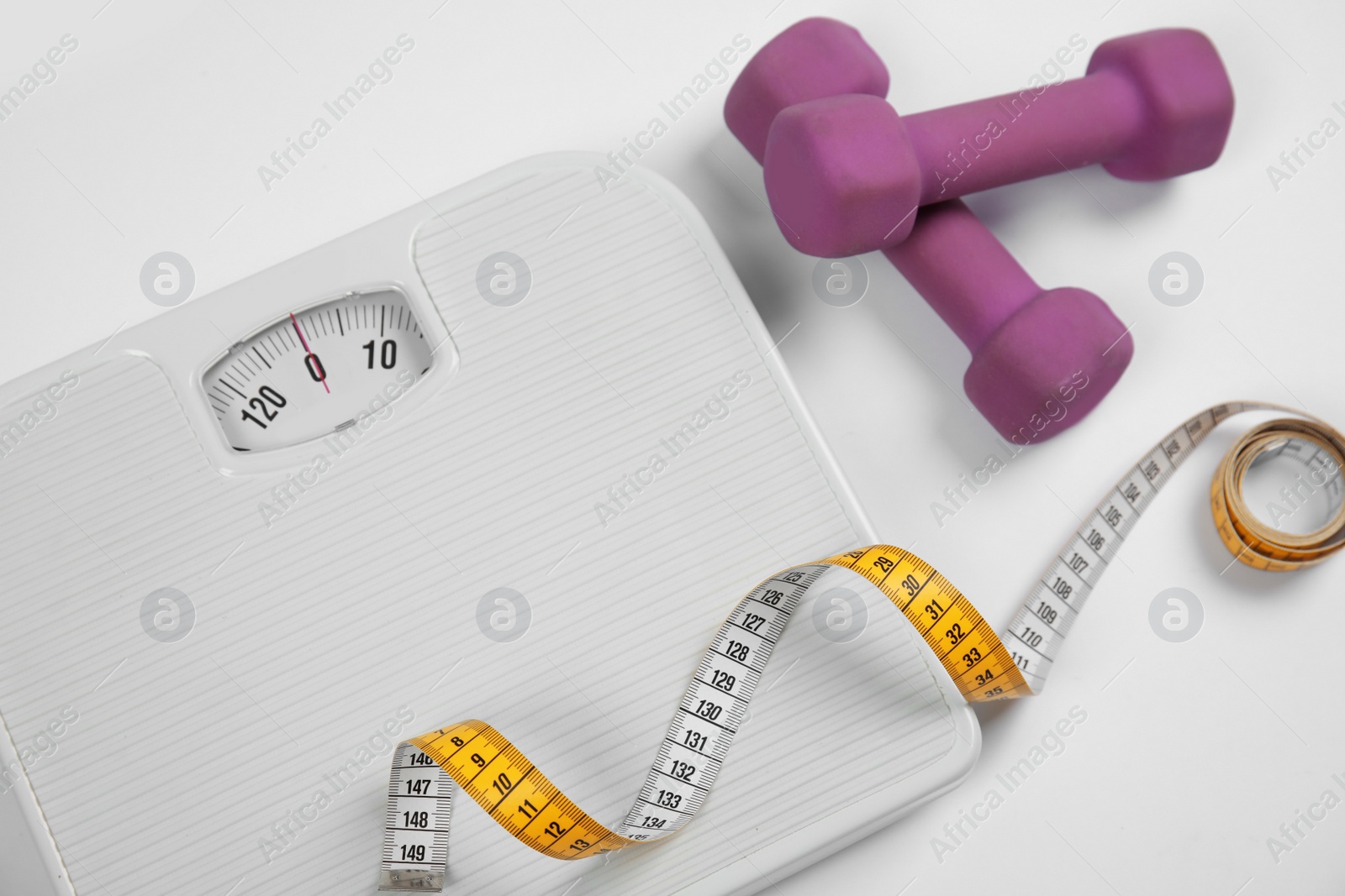 Photo of Modern scales, tape measure and dumbbells on white background