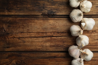 Photo of Fresh organic garlic on wooden table, flat lay. Space for text