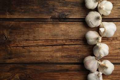 Fresh organic garlic on wooden table, flat lay. Space for text