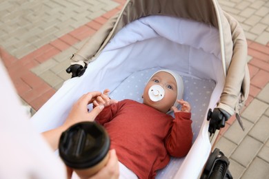 Young mother walking with her baby in stroller outdoors, closeup