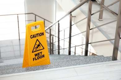 Safety sign with phrase Caution wet floor on stairs. Cleaning service