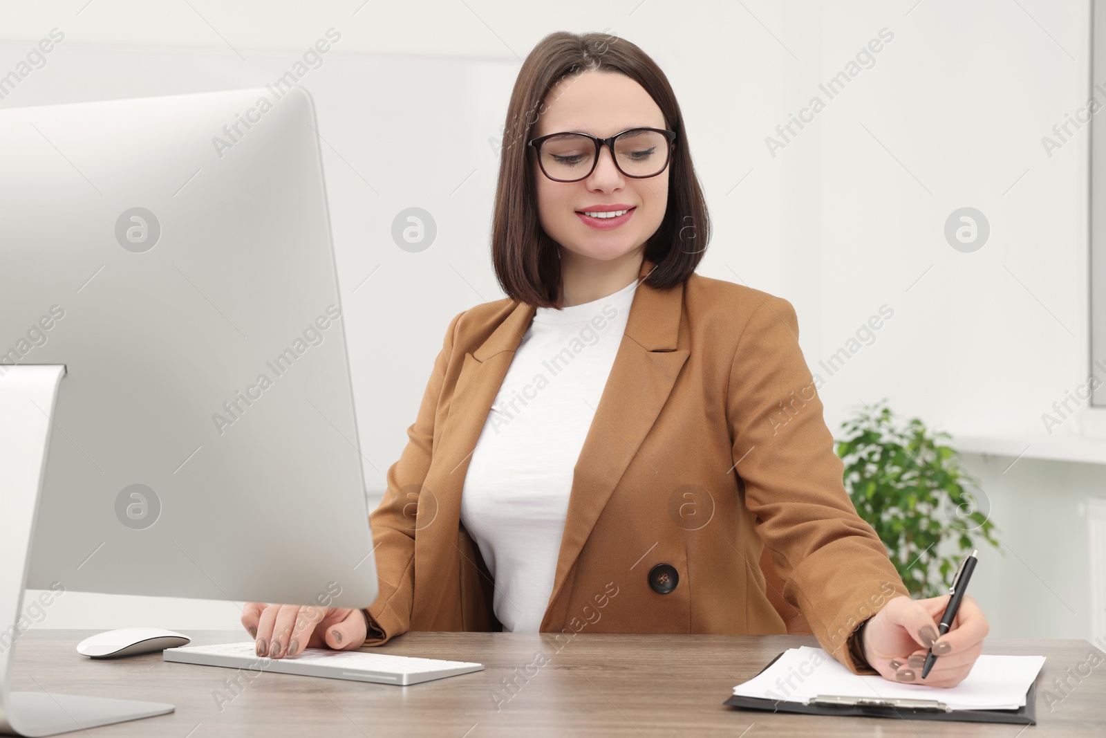 Photo of Happy young intern working at table in modern office