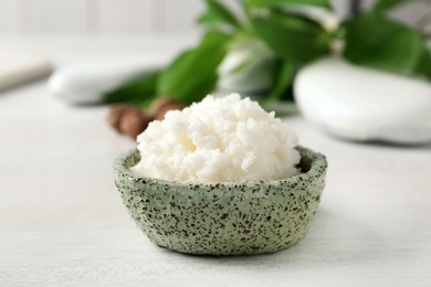 Shea butter in bowl on white table, closeup