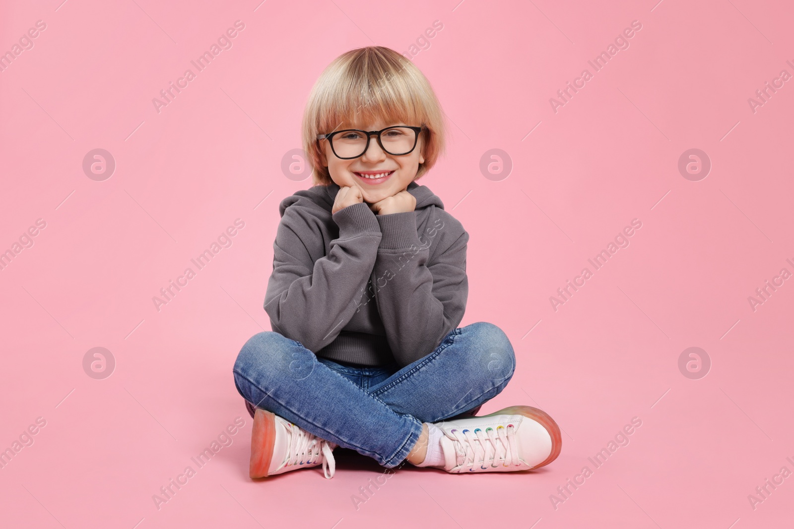 Photo of Cute little boy wearing glasses on pink background