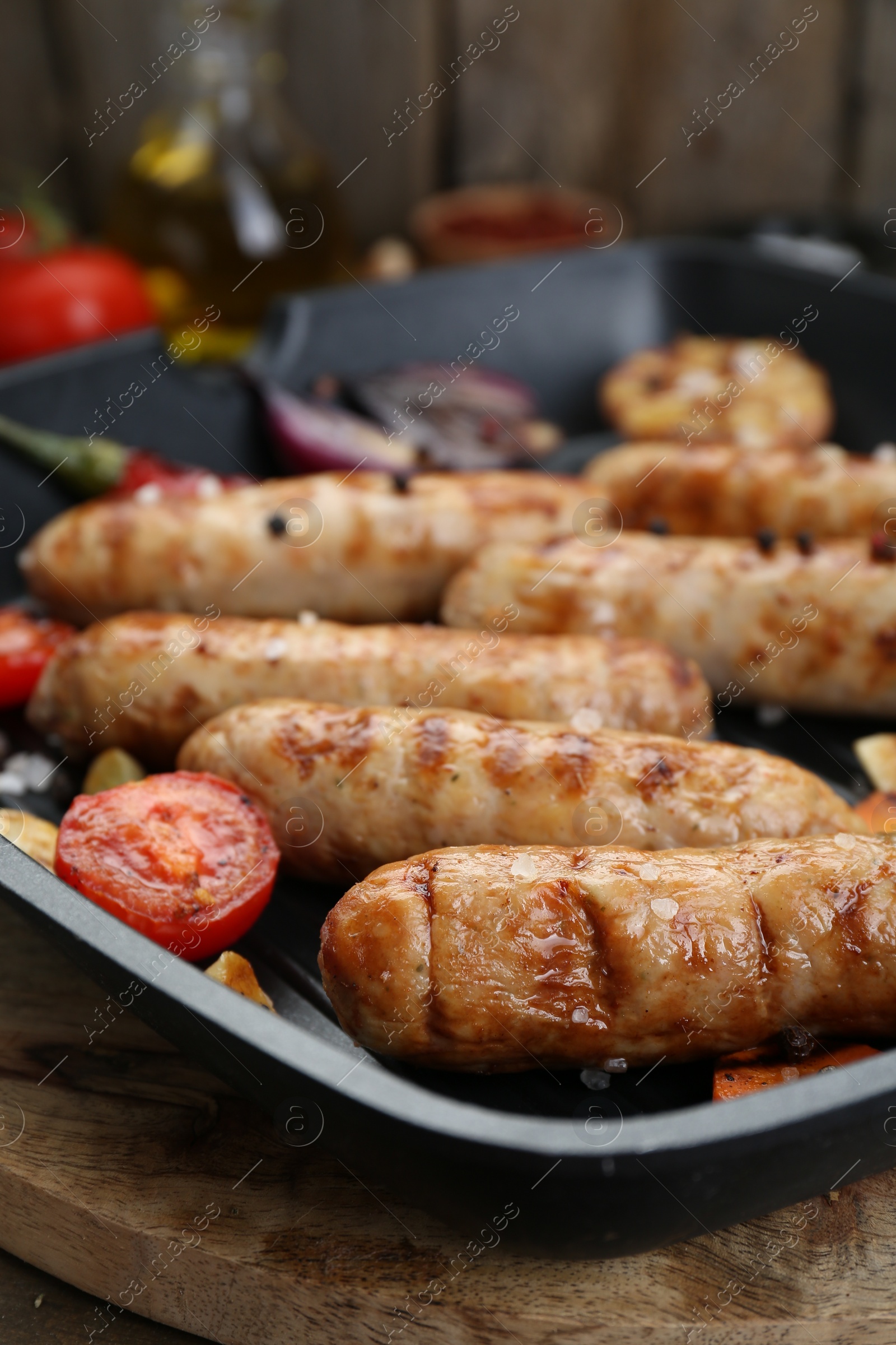 Photo of Tasty grilled sausages with vegetables on wooden table, closeup