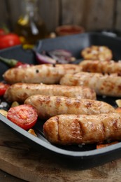 Tasty grilled sausages with vegetables on wooden table, closeup