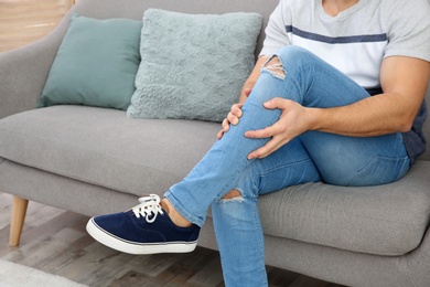 Photo of Man suffering from leg pain at home, closeup. Space for text