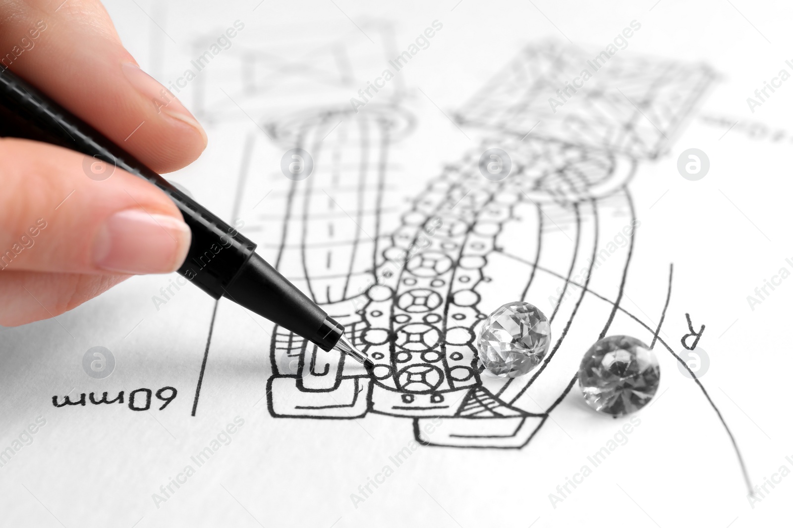 Photo of Jeweler drawing sketch of elegant earrings on paper, closeup