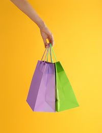 Woman with paper shopping bags on yellow background, closeup