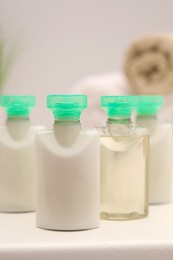 Photo of Mini bottles of cosmetic products on white table against blurred background, closeup