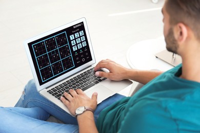 Image of Man playing sudoku game on laptop indoors, closeup