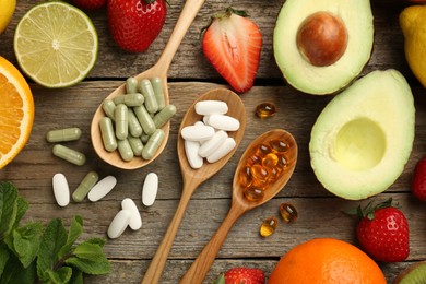 Photo of Different vitamin pills and fresh fruits on old wooden table, flat lay