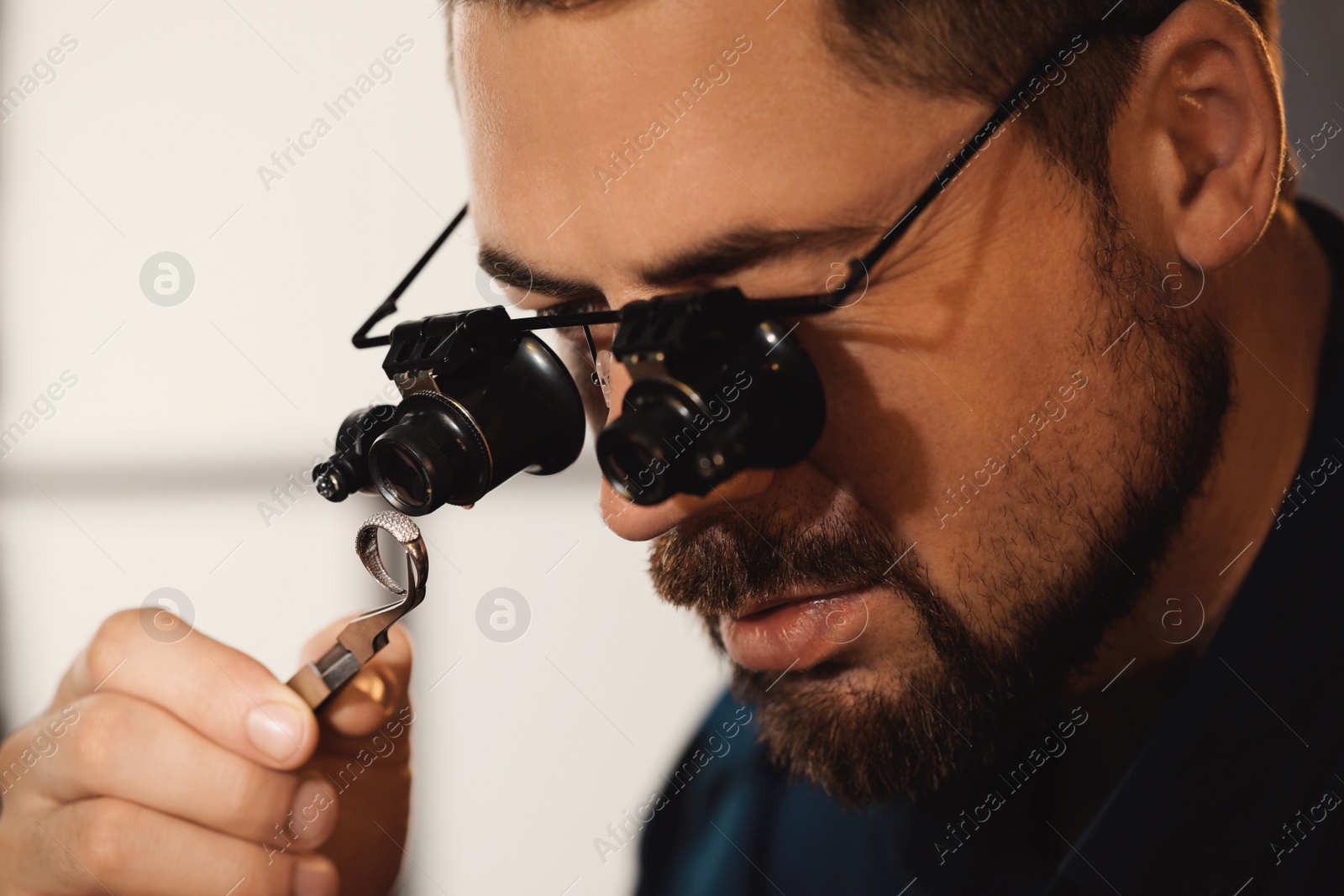 Photo of Jeweler working with ring on blurred background, closeup