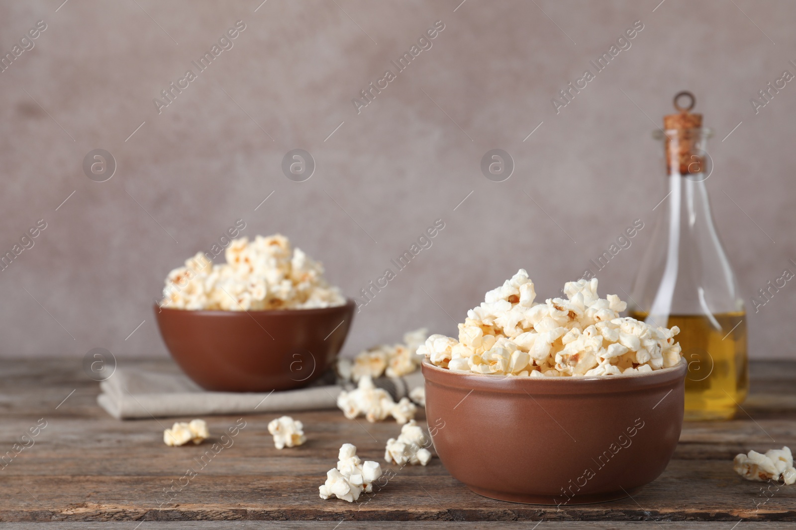 Photo of Bowl with tasty popcorn on wooden table. Space for text