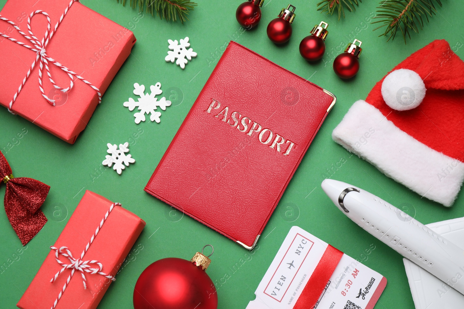 Photo of Flat lay composition with toy airplane, passport and festive decor on green background. Christmas vacation