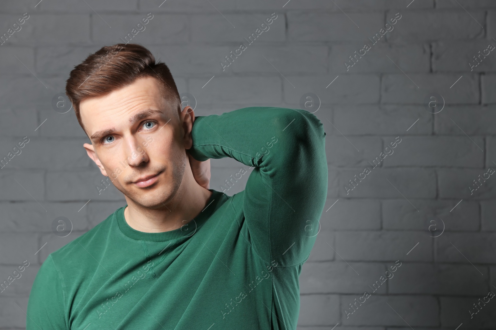 Photo of Portrait of young man with beautiful hair on brick wall background