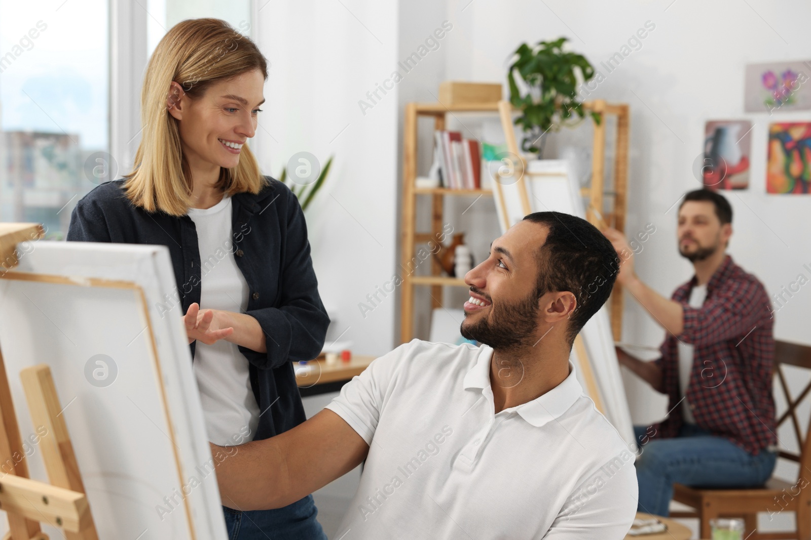 Photo of Artist and her students having painting class in studio. Creative hobby