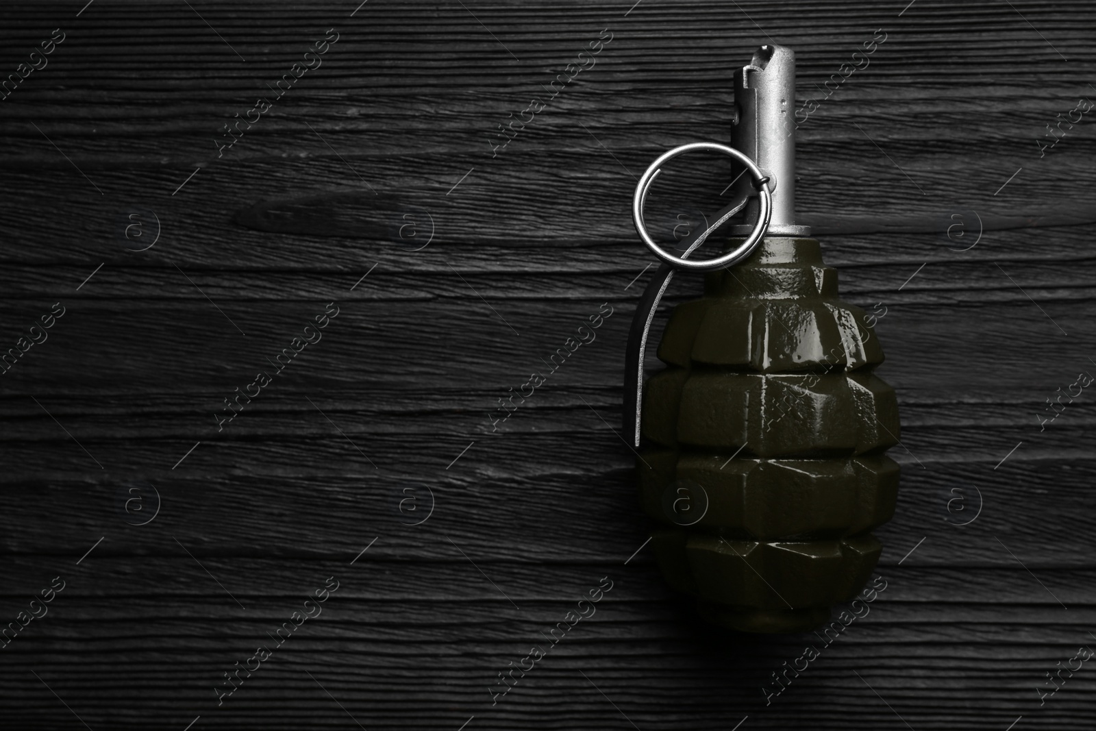 Photo of Hand grenade on black wooden table, top view. Space for text