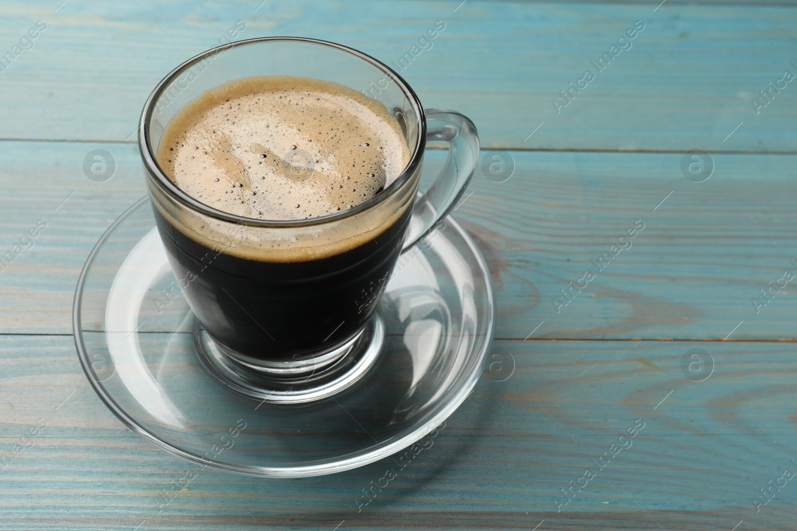 Photo of Cup of aromatic coffee on light blue wooden table, closeup. Space for text