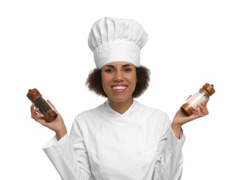Happy female chef in uniform holding shakers with pepper and salt on white background
