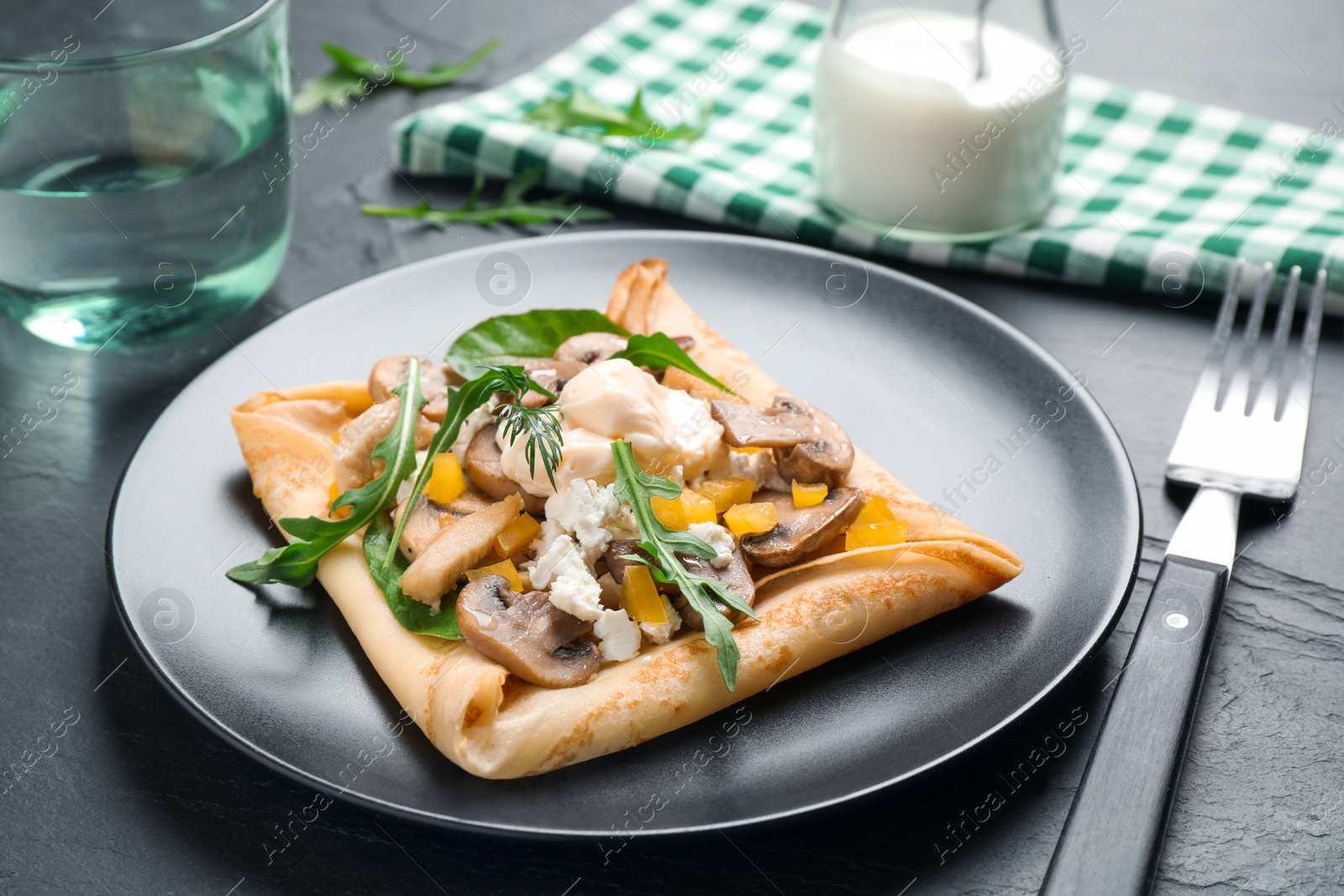 Photo of Delicious breakfast with thin pancakes on black table