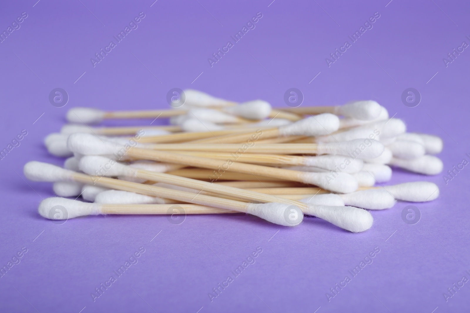 Photo of Many wooden cotton buds on violet background