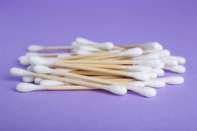 Photo of Many wooden cotton buds on violet background