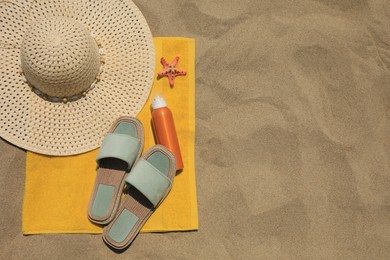 Sunscreen, starfish and beach accessories on sand, top view with space for text. Sun protection care