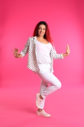 Beautiful Hispanic woman dancing on pink background
