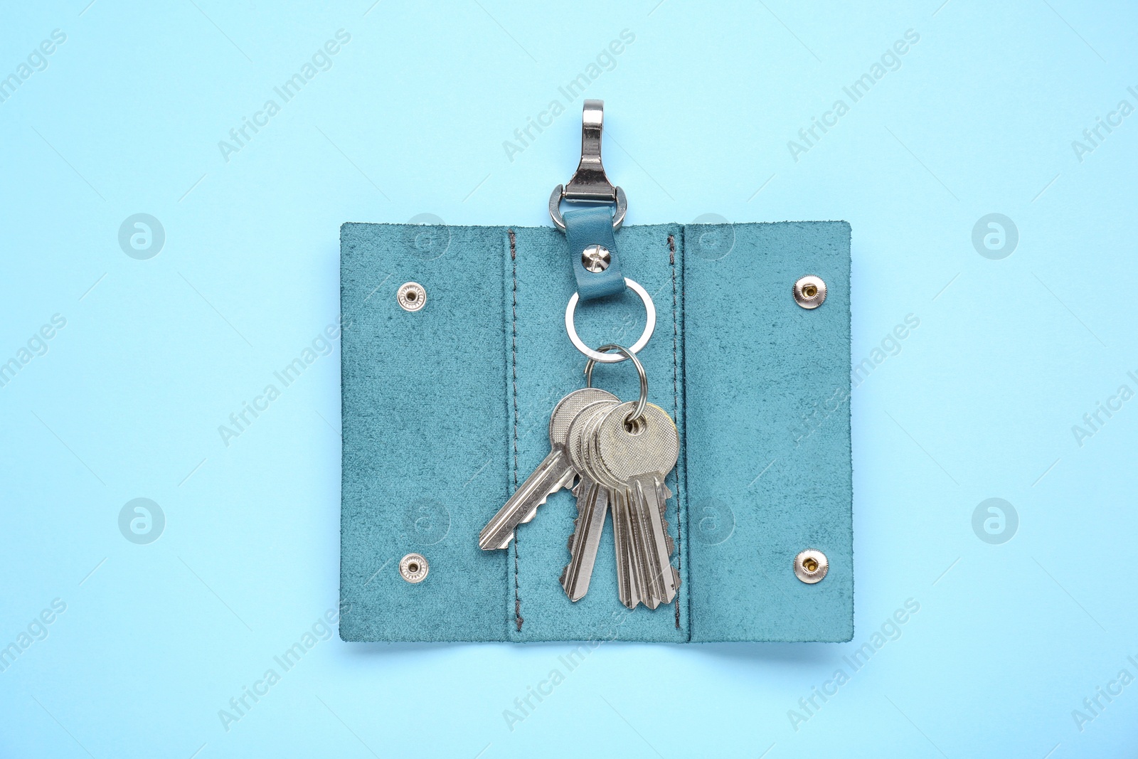 Photo of Leather holder with keys on light blue background, top view