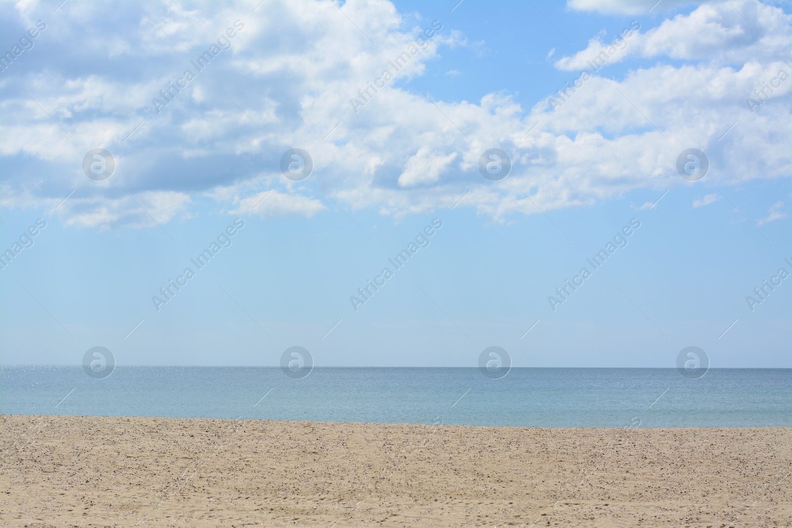 Photo of Picturesque view of sandy beach near calm sea on cloudy day