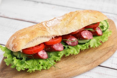 Photo of Delicious sandwich with sausages and vegetables on white table, closeup