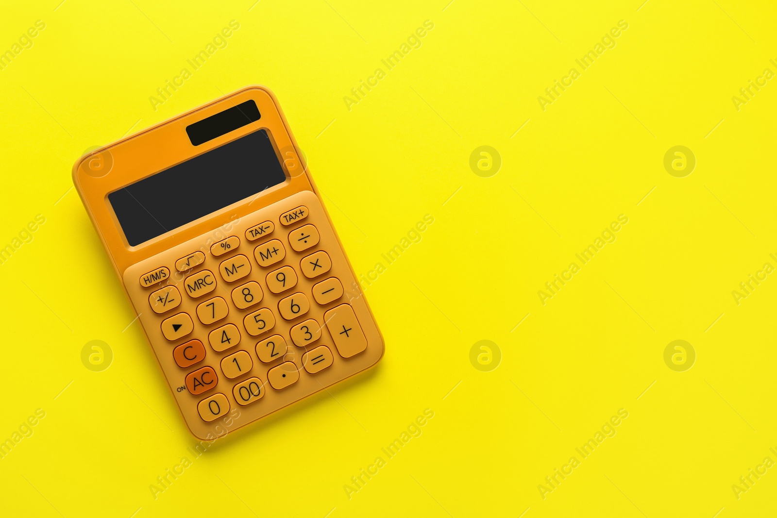 Photo of Orange calculator on yellow background, top view. Space for text