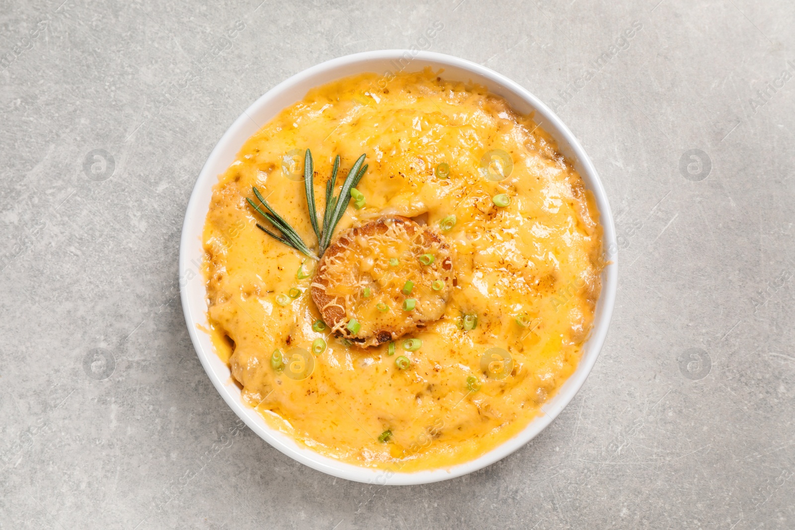 Photo of Tasty homemade French onion soup on grey table, top view