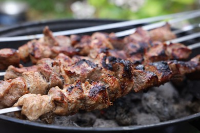 Photo of Cooking delicious kebab on metal brazier outdoors, closeup