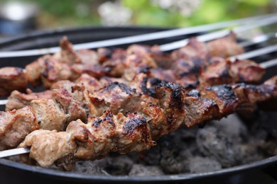 Cooking delicious kebab on metal brazier outdoors, closeup