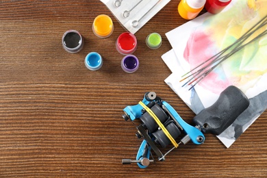 Flat lay composition with tattoo machine and space for text on wooden background