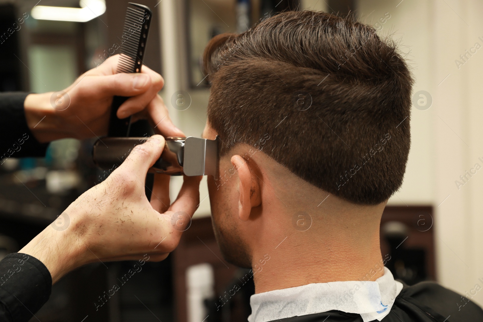 Photo of Professional hairdresser making stylish haircut in salon, back view