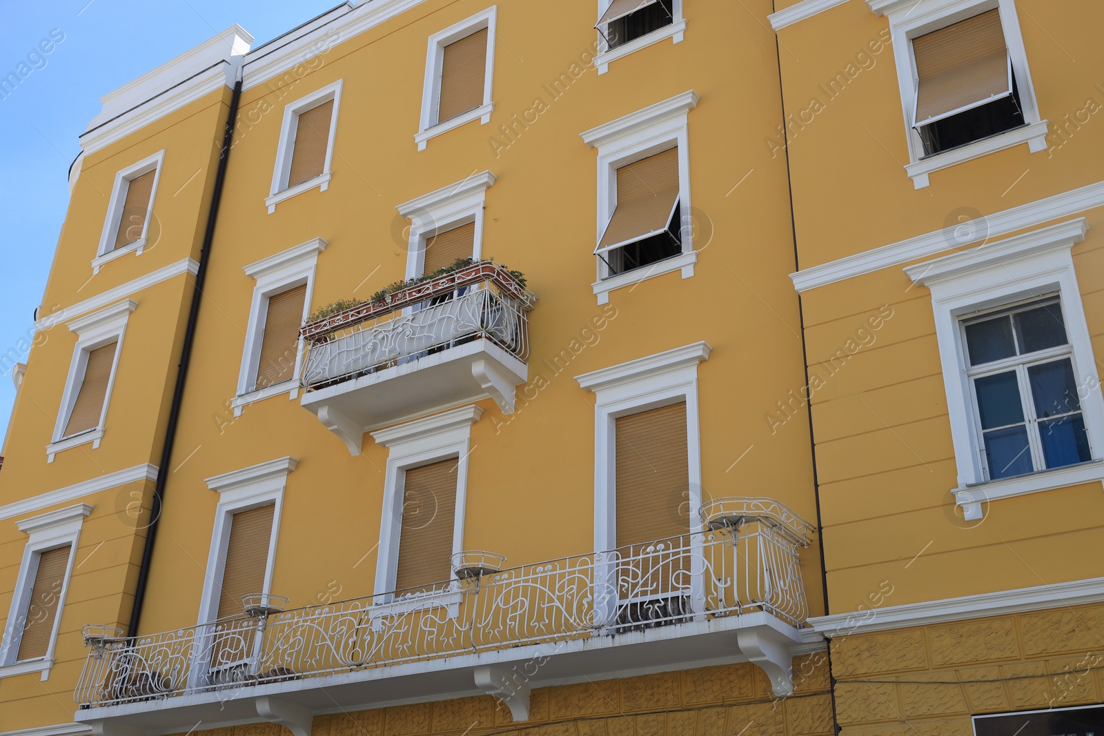 Photo of Beautiful yellow building with balconies outdoors, low angle view