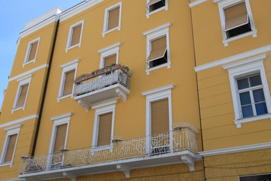 Beautiful yellow building with balconies outdoors, low angle view