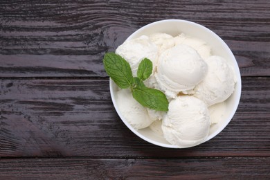 Photo of Delicious vanilla ice cream and mint in bowl on wooden table, top view. Space for text