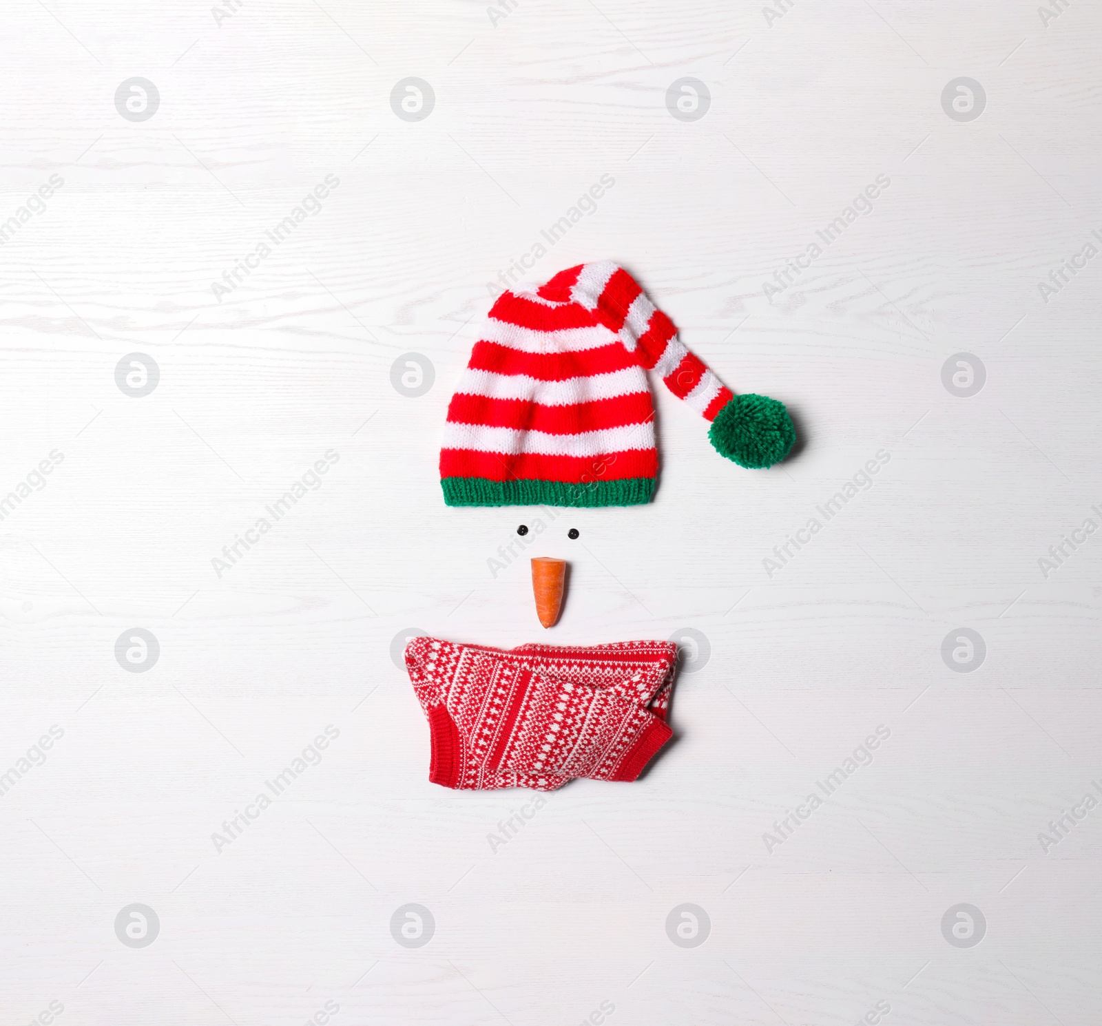 Photo of Funny snowman made with different elements on white wooden background, flat lay