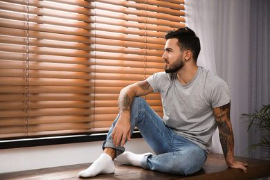 Young man relaxing near window at home