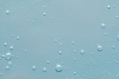 Photo of Transparent cleansing gel on dusty light blue background, top view. Cosmetic product