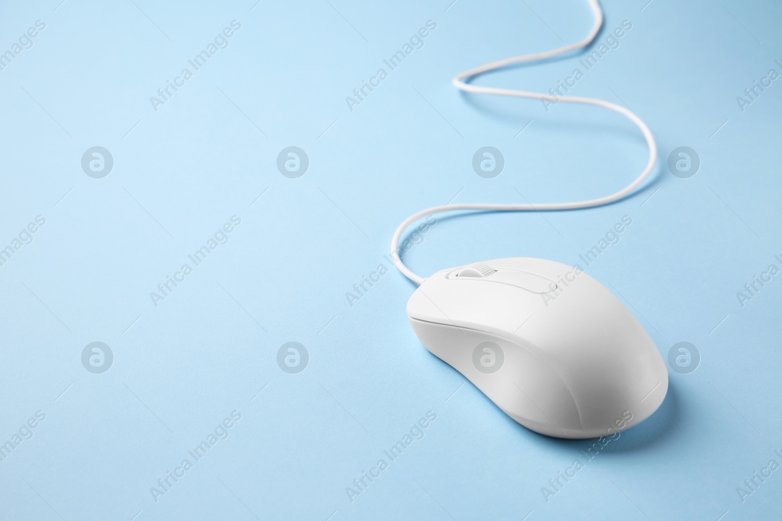 Photo of One wired mouse on light blue background. Space for text