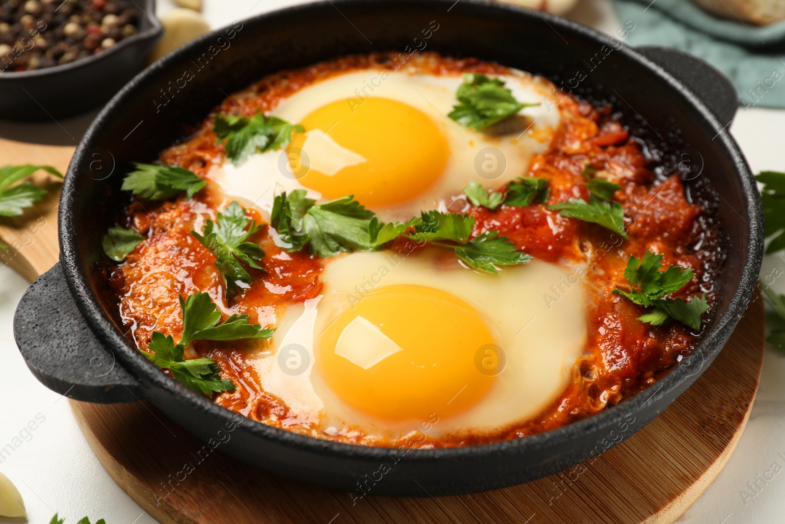 Photo of Delicious shakshuka in frying pan on white table, closeup