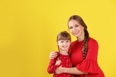 Happy woman and daughter in stylish clothes on color background, space for text