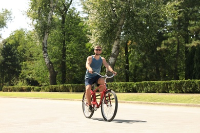 Photo of Attractive man riding bike outdoors on sunny day