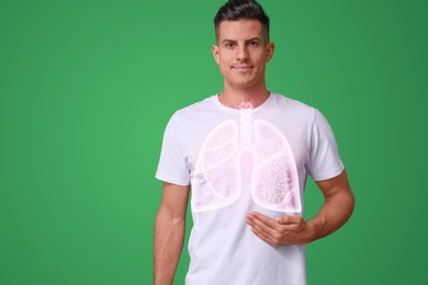 Image of Handsome man holding hand near chest with illustration of lungs against green background