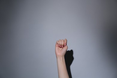Photo of SOS gesture. Woman showing signal for help on grey background, closeup
